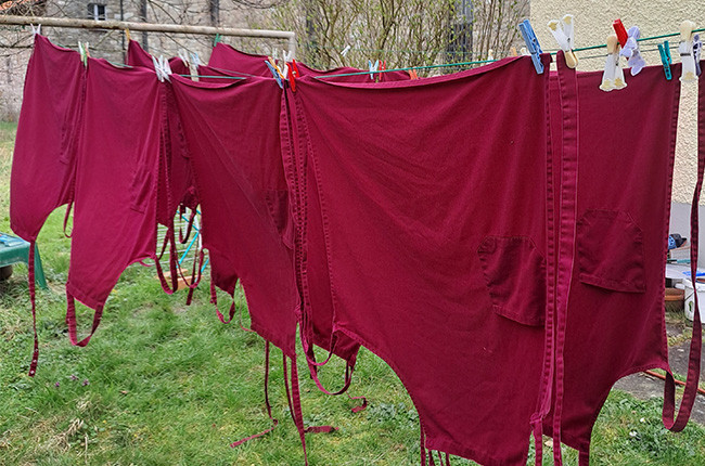 Rote Kochschürzen hängen auf Wäscheleine im Garten